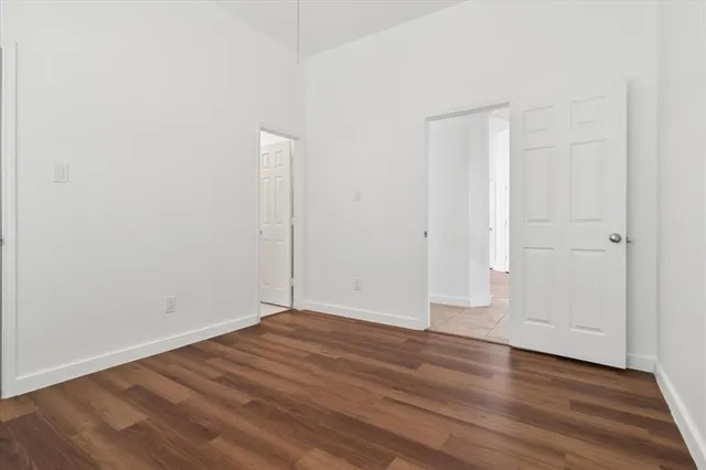 a view of an empty room with wooden floor and closet