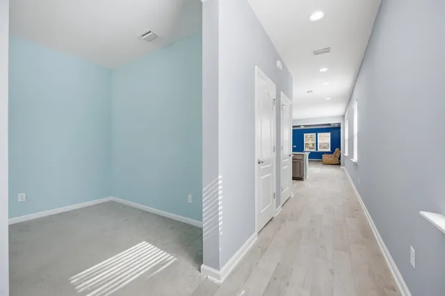 a view of a hallway with wooden floor and a living room