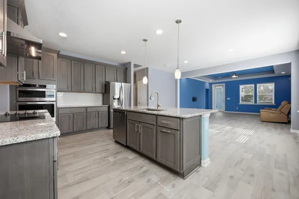 a kitchen with stainless steel appliances kitchen island granite countertop a refrigerator a stove a sink and a oven