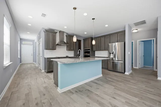 a kitchen with kitchen island stainless steel appliances a sink cabinets and wooden floor