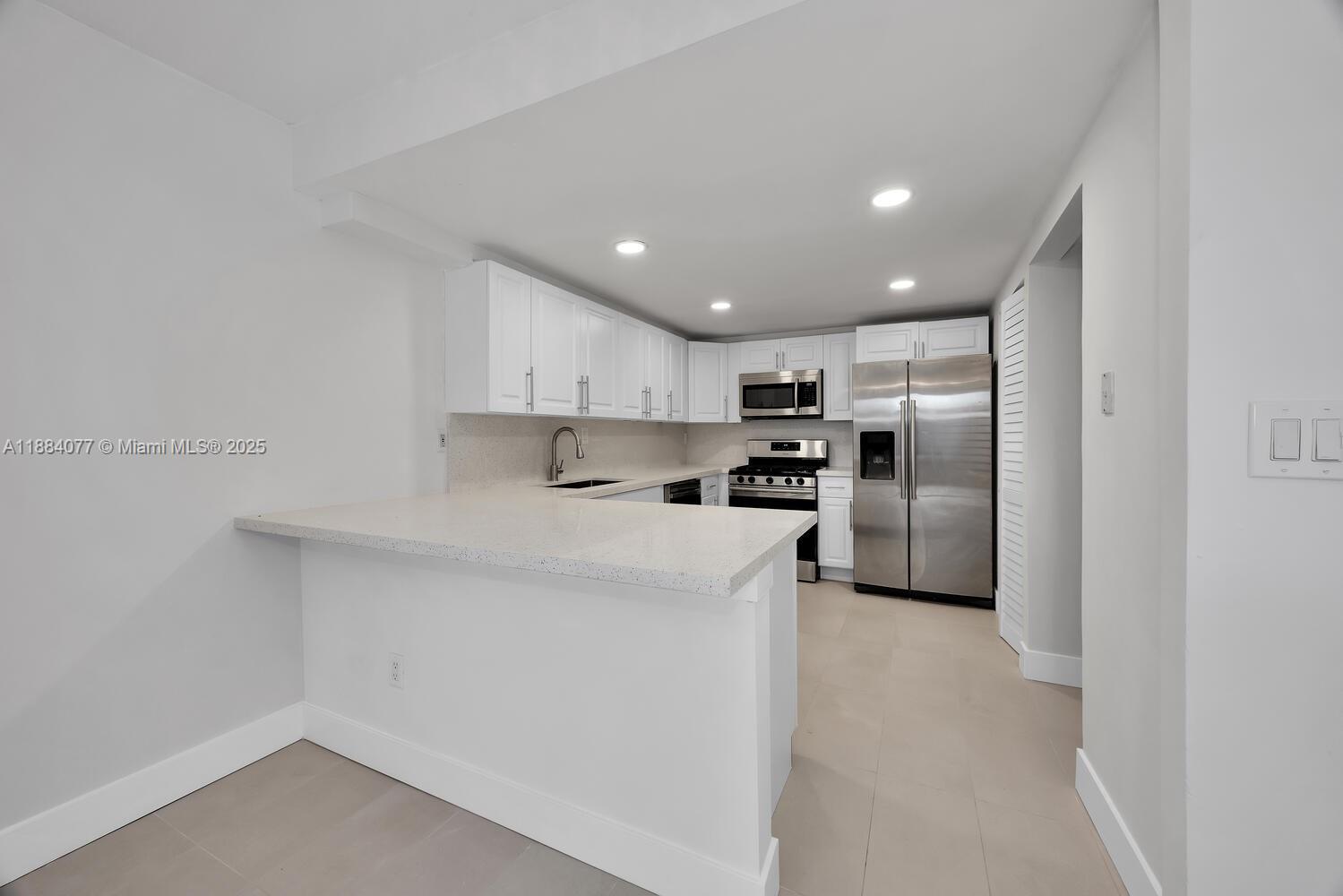 11500 Southwest 64th Street, Unit H Miami, FL 33173 - Photo 9 of 38 a kitchen with stainless steel appliances refrigerator a microwave and sink