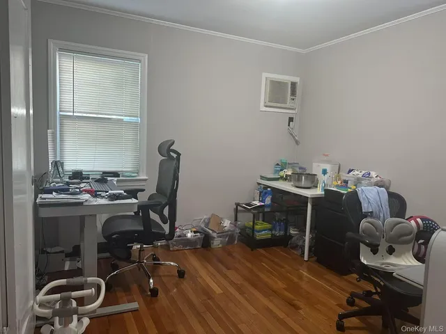 a view of a hallway to a livingroom with wooden floor and furniture