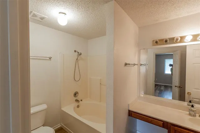 a bathroom with a granite countertop sink a toilet and shower