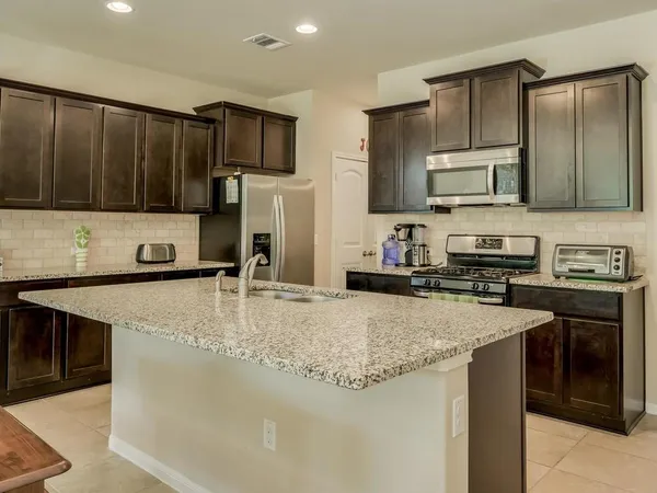 a kitchen with kitchen island granite countertop a stove sink and cabinets