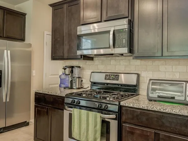 a kitchen with kitchen island granite countertop a stove sink and refrigerator