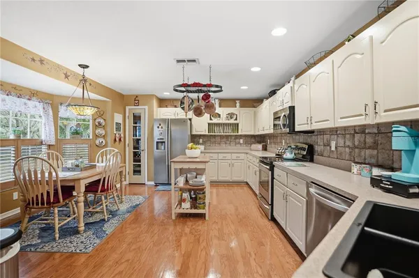 a kitchen with stainless steel appliances a dining table chairs stove and white cabinets