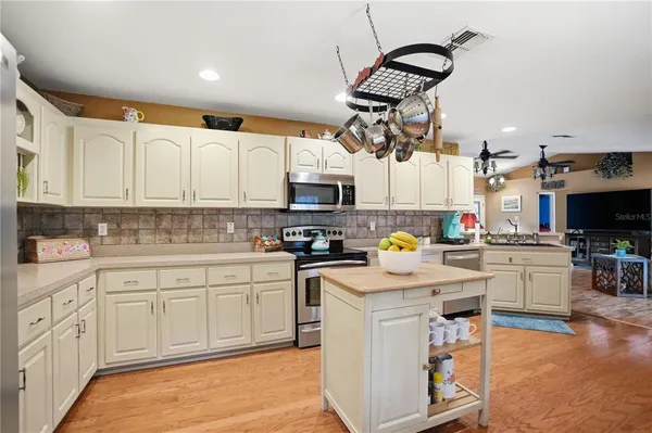 a kitchen with granite countertop white cabinets stainless steel appliances and wooden floor