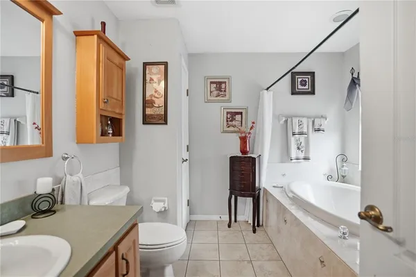 a bathroom with a granite countertop sink mirror vanity bathtub and a toilet