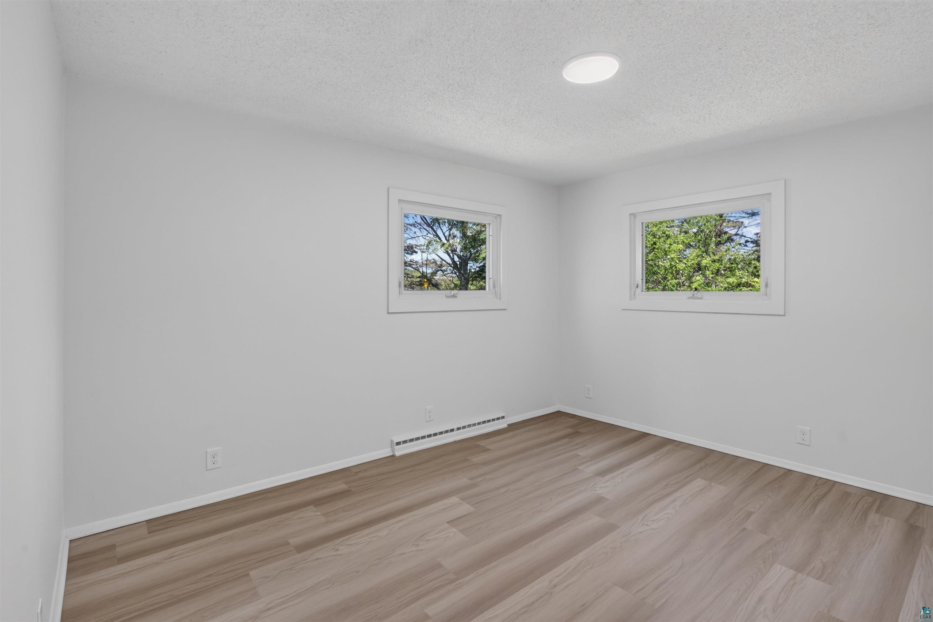 5868 Rice Lake Road Duluth, MN 55803 - Photo 25 of 39 Bright room featuring two windows, wood-finish flooring, white baseboards, and a recessed ceiling light