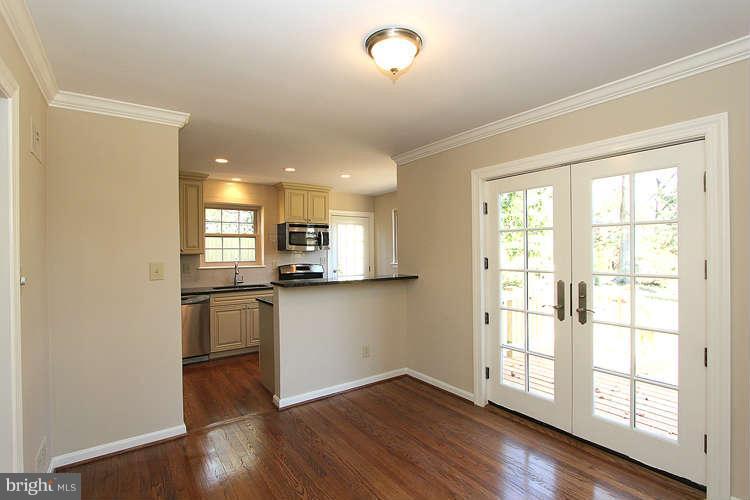 8817 Walnut Hill Road Chevy Chase, MD 20815 - Photo 6 of 26 a view of a kitchen and an empty room with wooden floor and windows