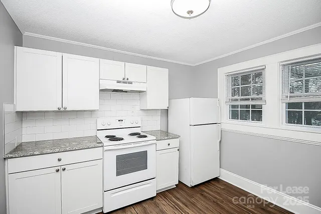 a white kitchen with wooden floor and white stainless steel appliances
