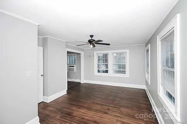 a view of an empty room with a window and wooden floor