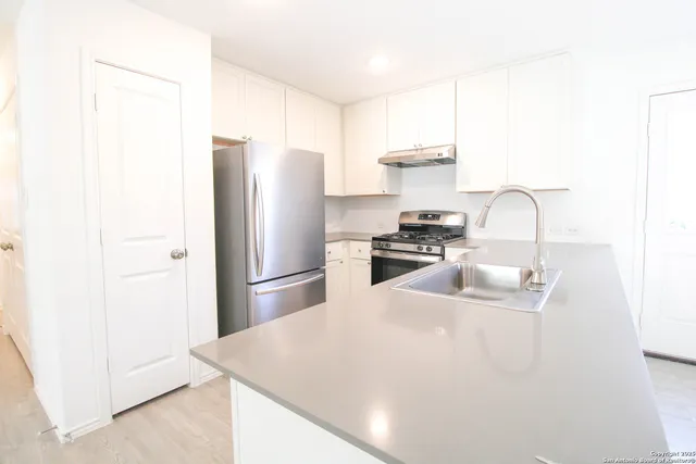 a kitchen with stainless steel appliances granite countertop a sink a stove a refrigerator a washer and dryer