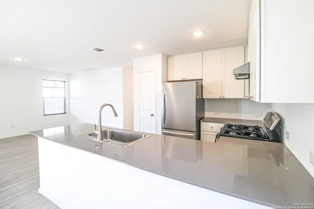 a kitchen with granite countertop a sink a refrigerator and cabinets
