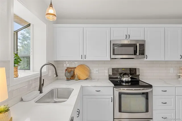 a kitchen with stainless steel appliances granite countertop a sink a stove a microwave and cabinets