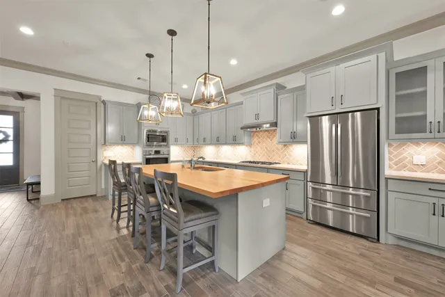 a kitchen with stainless steel appliances granite countertop a table chairs and a refrigerator