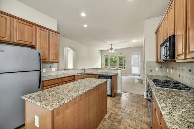 a kitchen with stainless steel appliances granite countertop a sink stove and refrigerator