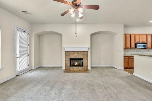 a view of a livingroom with a fireplace a ceiling fan and windows
