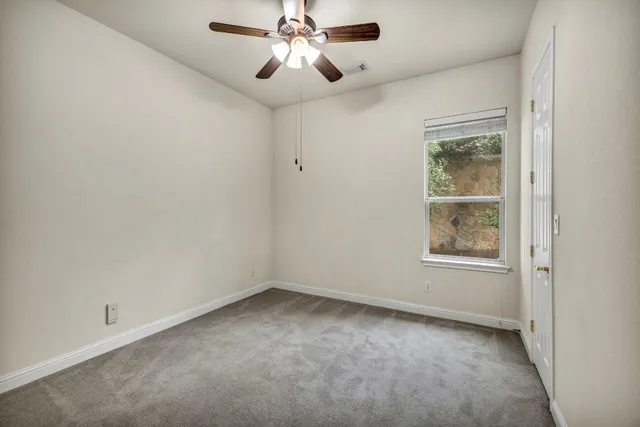 an empty room with a window and a fan