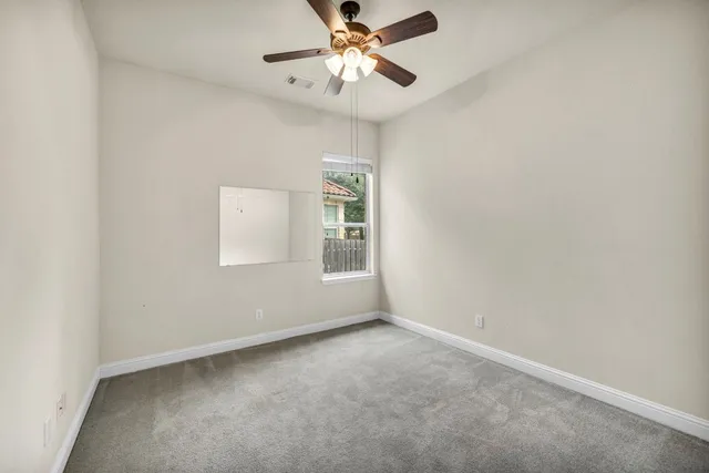 an empty room with a window and a ceiling fan