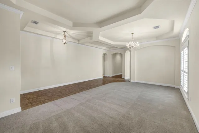 a view of a big room with a chandelier fan and windows