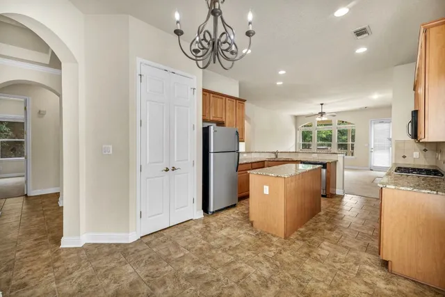 a kitchen with stainless steel appliances granite countertop a refrigerator a sink dishwasher a oven and a dining table with wooden floor