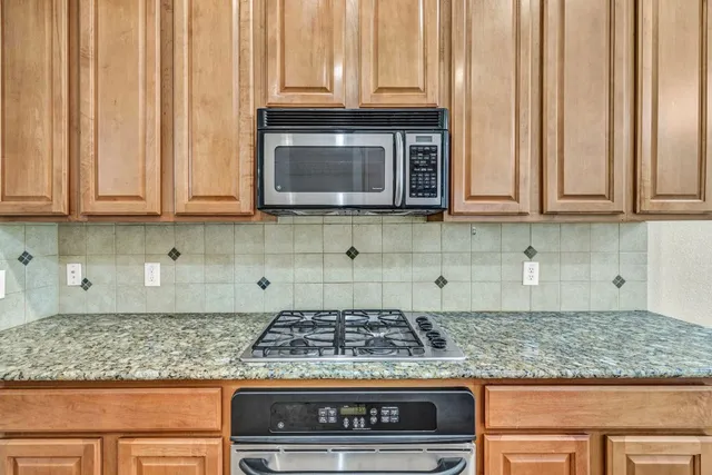 a kitchen with granite countertop a stove a microwave and cabinets