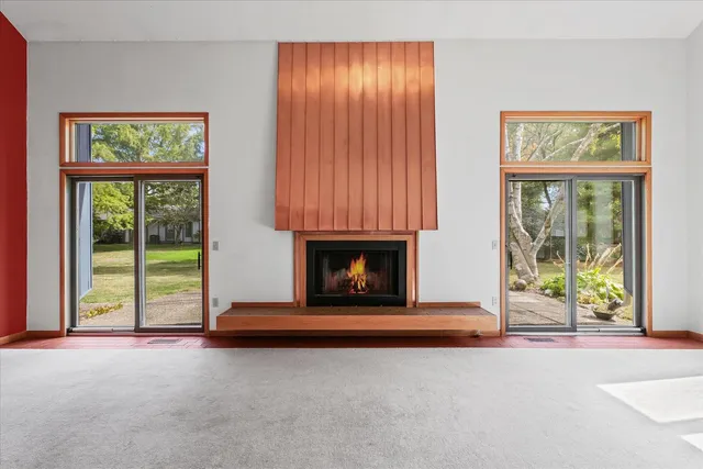 an empty room with floor to ceiling windows and fireplace