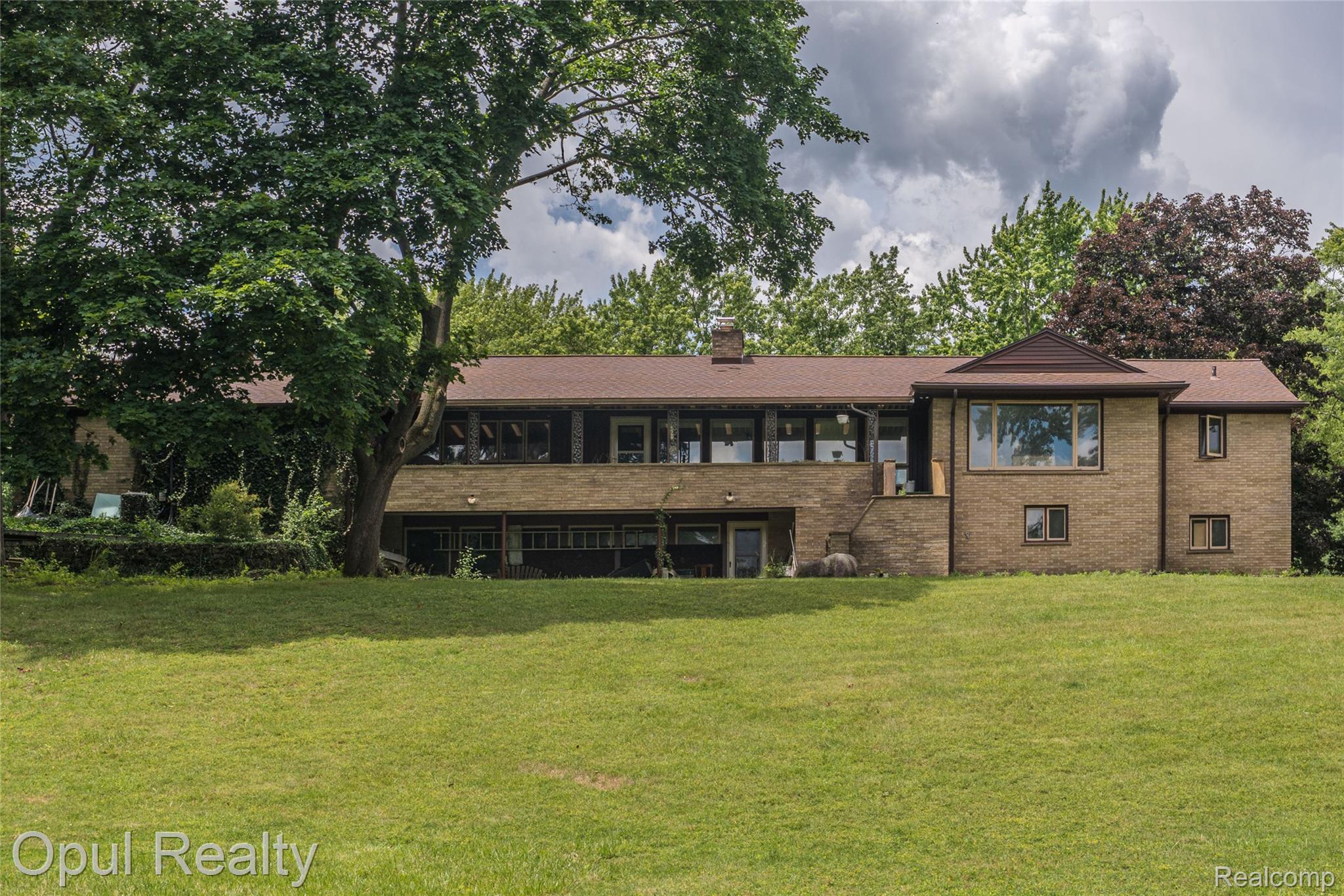 6455 Norham Road Bloomfield Hills, MI 48301 - Photo 7 of 93 Expansive green lawn with a brick exterior property featuring a covered patio, a lower level entry, and multiple windows