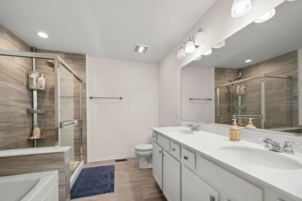 a spacious bathroom with a double vanity sink a toilet and a large mirror