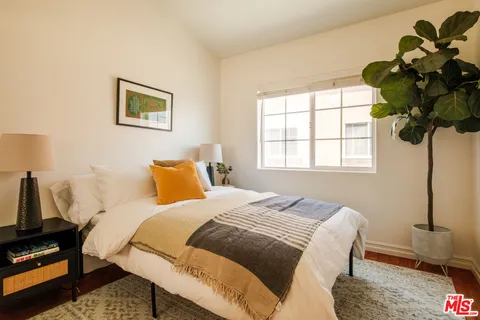 a bedroom with a bed a couch and potted plant