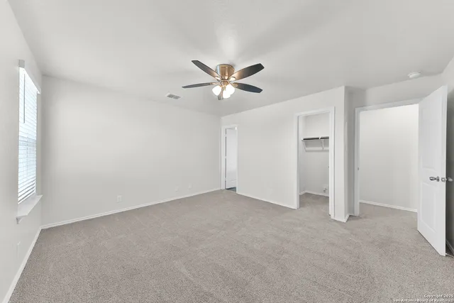 an empty room with closet and a ceiling fan