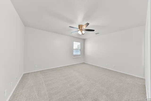 an empty room with a chandelier fan and windows