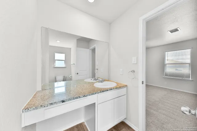 a bathroom with a granite countertop sink and a mirror