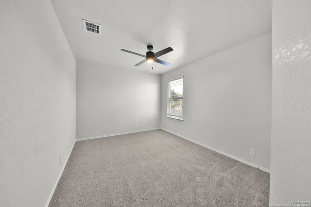 an empty room with windows and ceiling fan