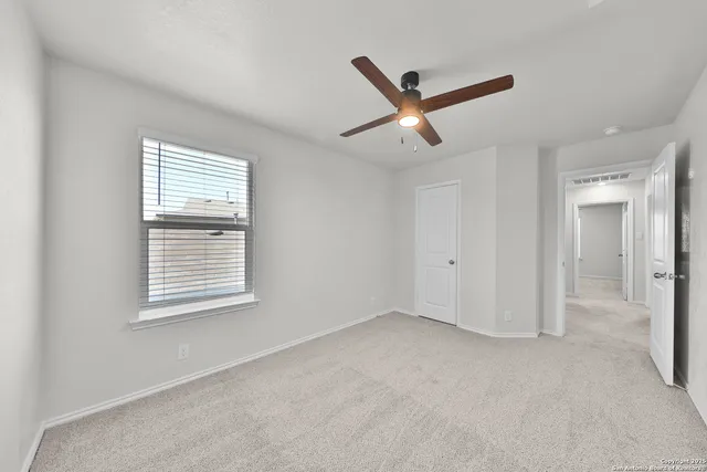 a view of empty room with windows and ceiling fan
