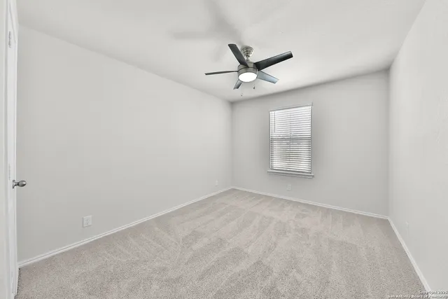 an empty room with a window and a ceiling fan