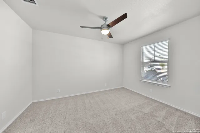 an empty room with a window and ceiling fan