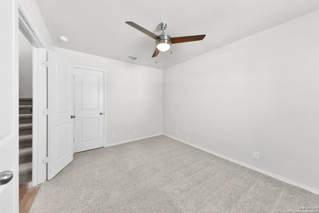 an empty room with a ceiling fan & a window