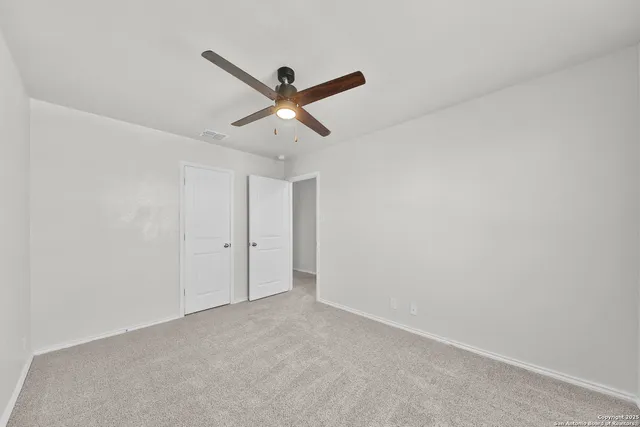 an empty room with a ceiling fan and a window