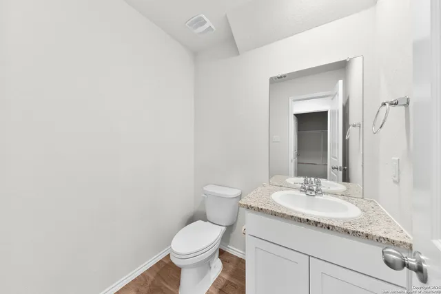 a bathroom with a granite countertop sink and a toilet