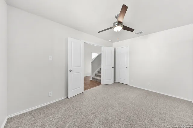 an empty room with chandelier fan and window
