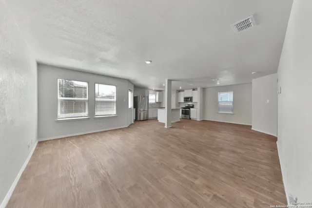 a view of an empty room with a window and wooden floor