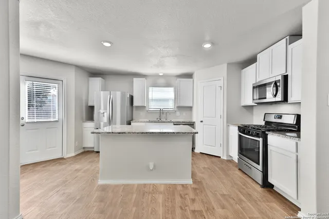 a kitchen with stainless steel appliances granite countertop a stove top oven a sink dishwasher and a refrigerator