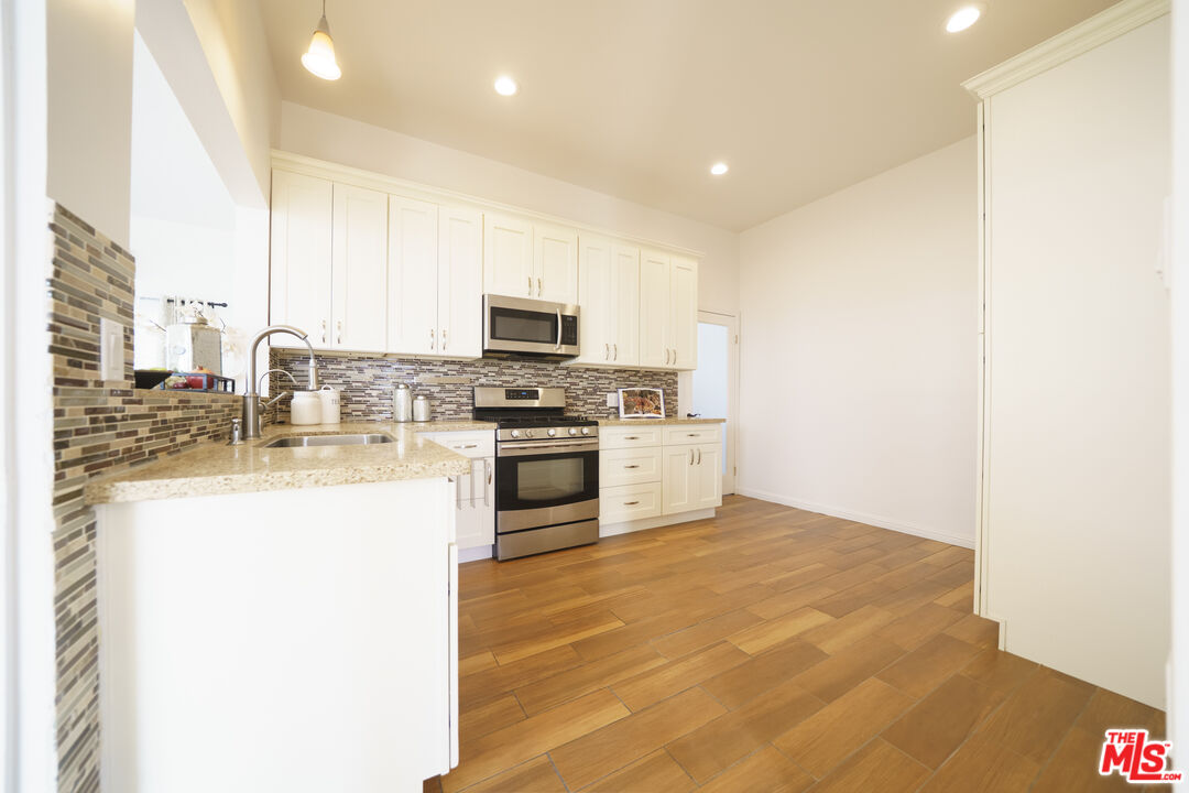 1159 South Norton Avenue Los Angeles, CA 90019 - Photo 17 of 39 a kitchen with stainless steel appliances a stove top oven a sink a refrigerator and a microwave