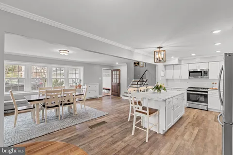 a kitchen with stainless steel appliances a refrigerator a stove a dining table and chairs