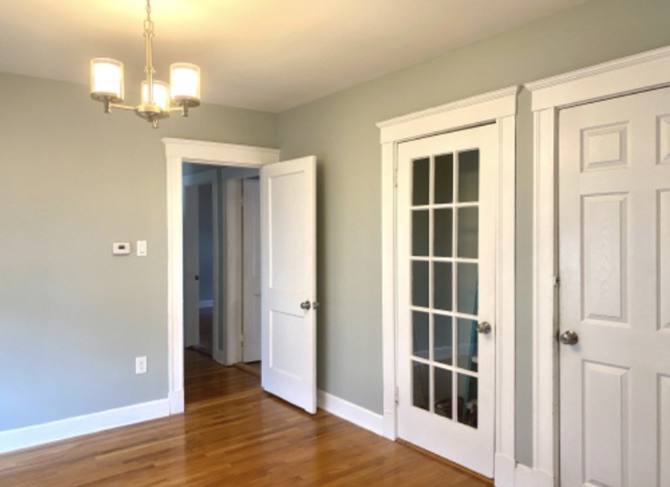 347 Vermont Street, Unit 2B Boston, MA 02132 - Photo 6 of 14 an empty room with wooden floor cabinet and windows