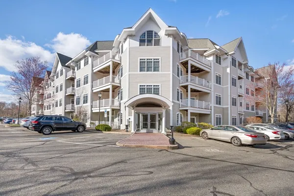 a front view of a building with cars parked