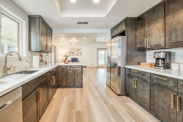 a large kitchen with a large window a sink stainless steel appliances and cabinets