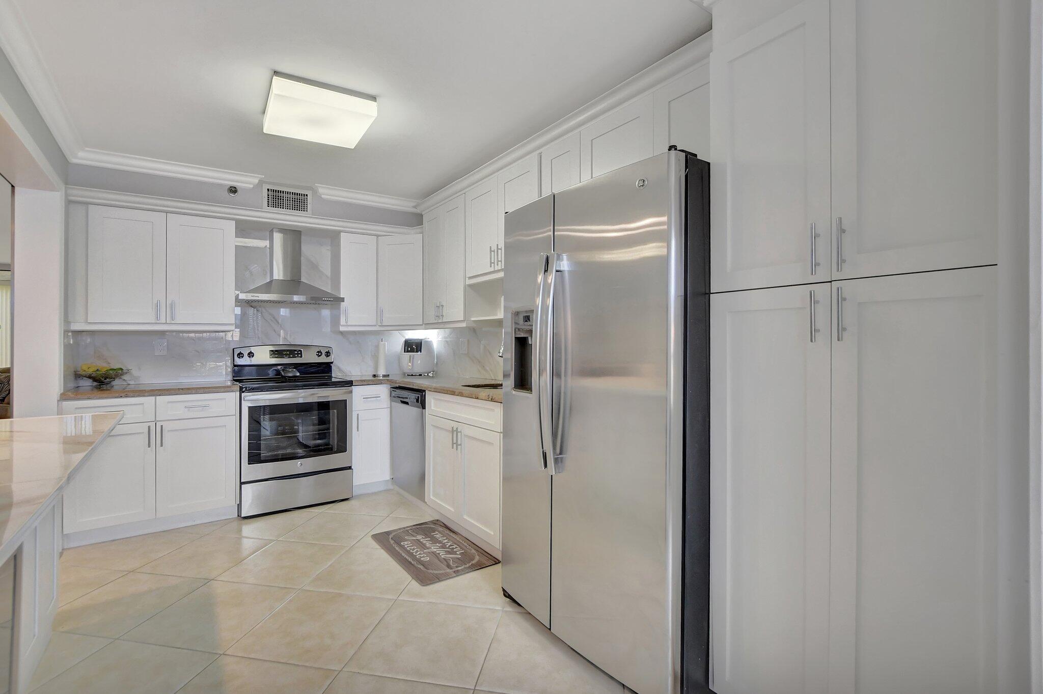 7194 Promenade Drive, Unit 102 Boca Raton, FL 33433 - Photo 13 of 56 a kitchen with a refrigerator sink and cabinets